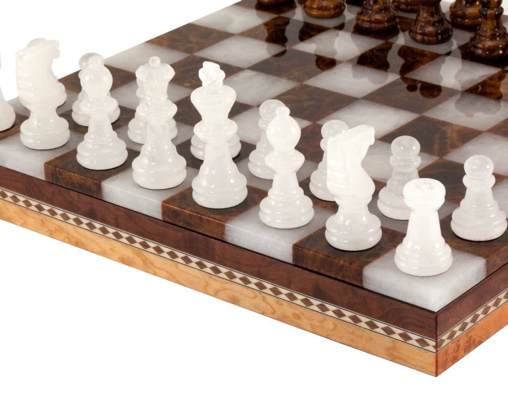 White alabaster chess pieces on a polished brown and white chessboard with inlaid wooden cabinet beneath.