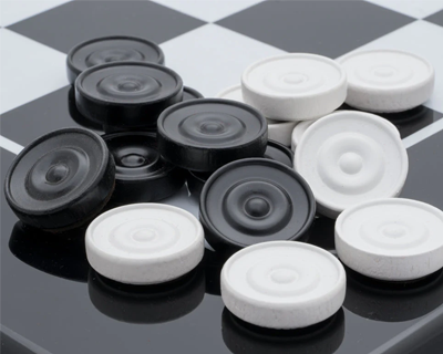 Close-up of black and white checkers pieces on a checkerboard.